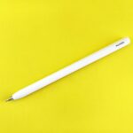 A white stylus pen rests on yellow background.